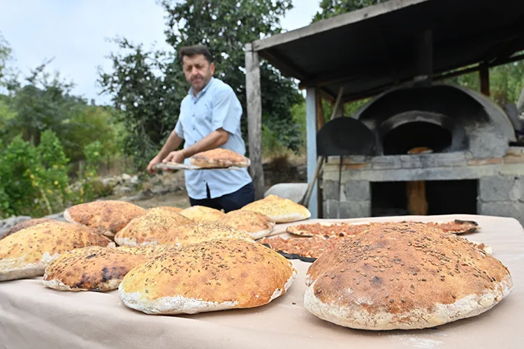 İmam taş fırında pişirdiği ekmekleri köylülere ikram ediyor
