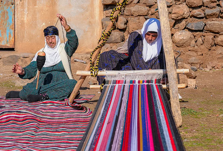 Evinin bahçesindeki tezgahta asırlık yöntemle kilim dokuyor